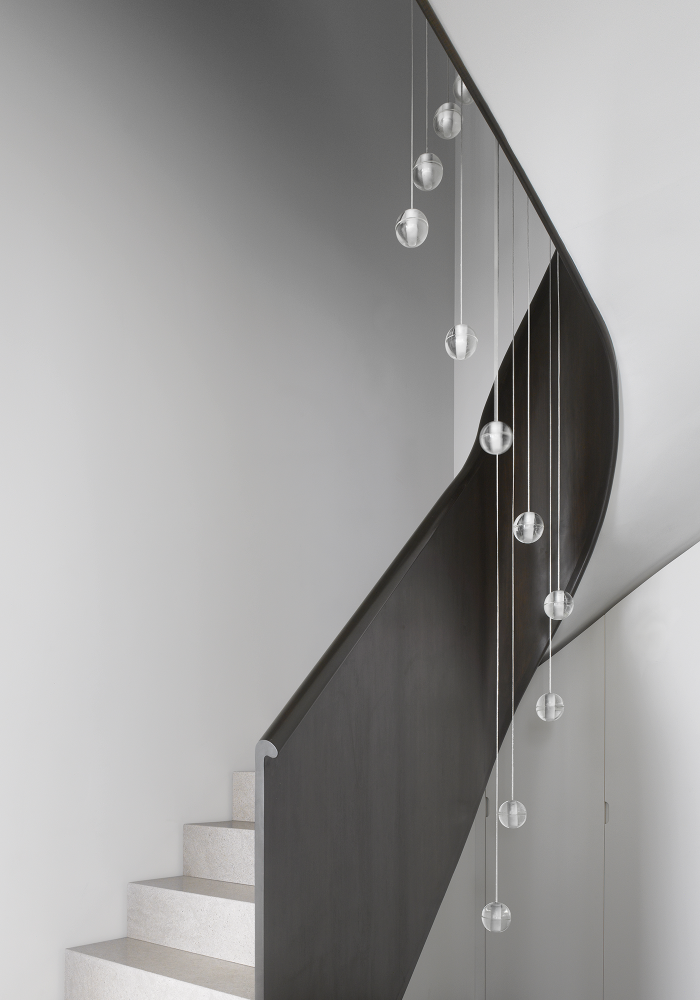 Shows a side view of a spiral staircase and hanging light in grey scale