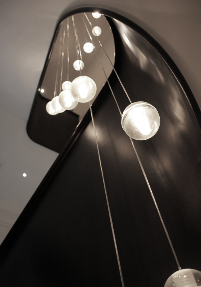 Shows an upward view of the hanging chandelier light on the staircase
