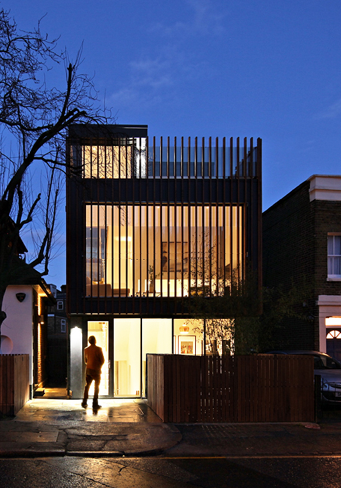 Shows an external view of the newly renovated new build house in Southwark at night